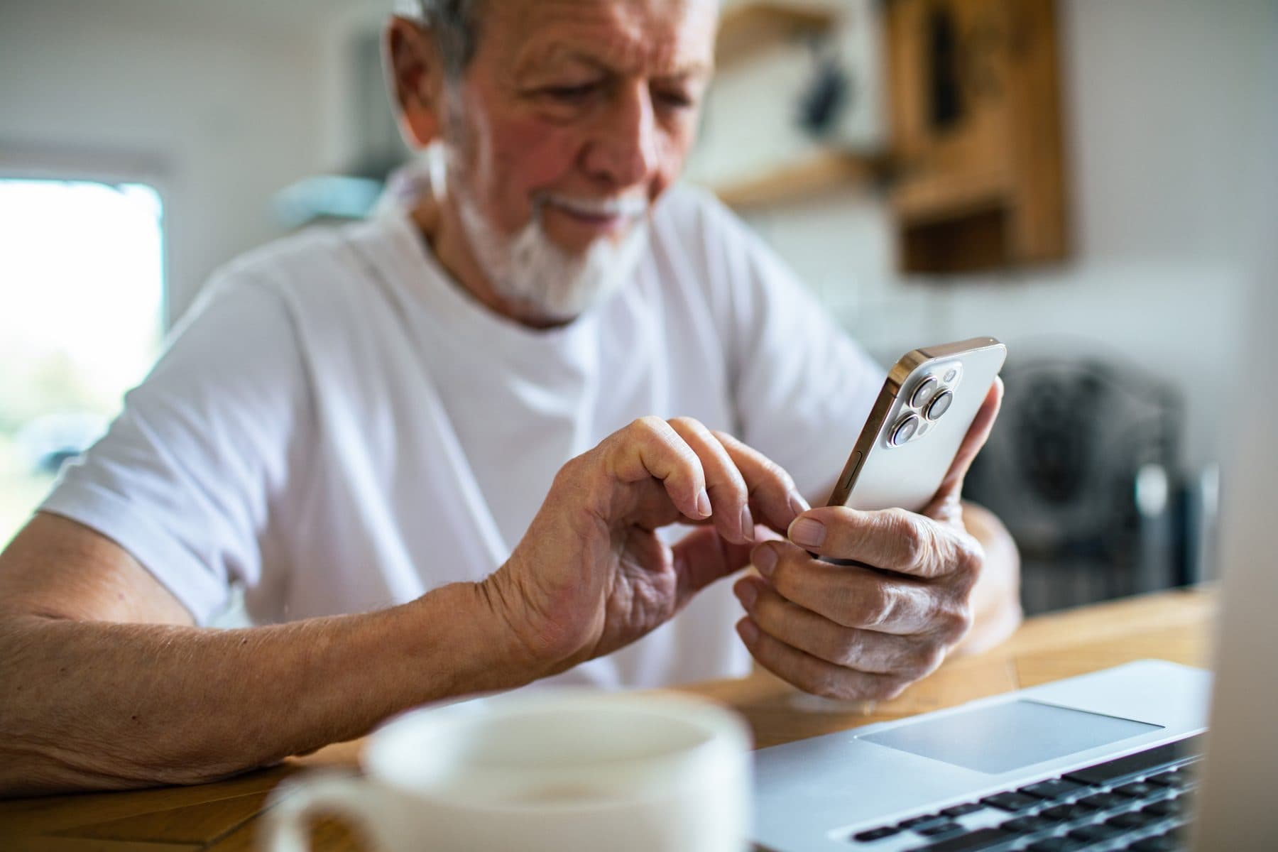 Older member checking in on his phone at his kitchen table